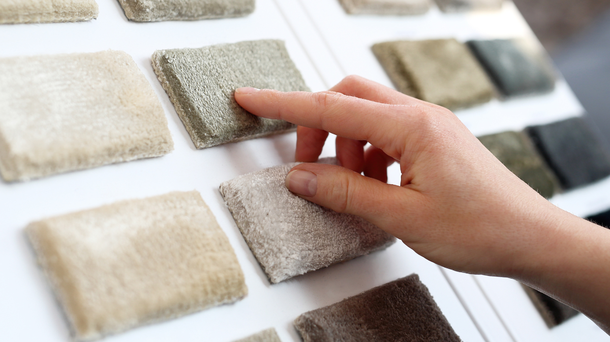 Hand Touching Carpet Sample on Sample Board